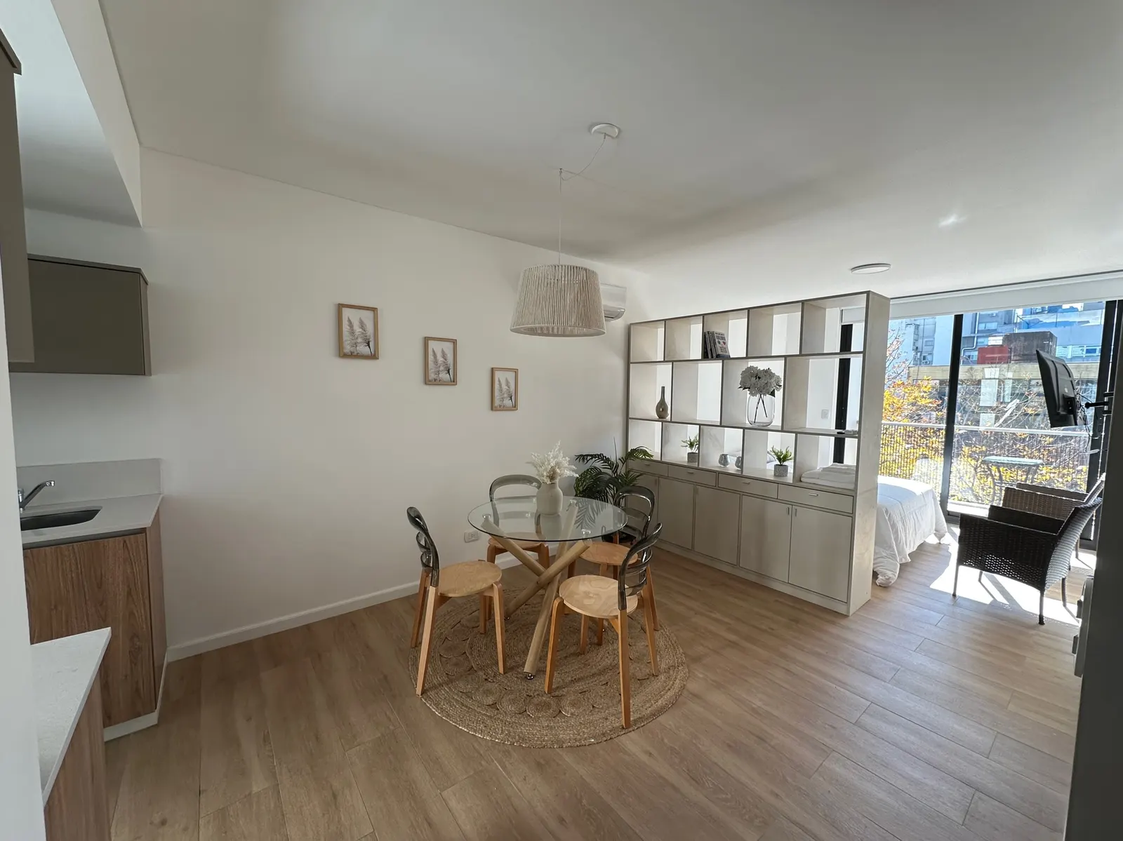 Monoambiente dividido de Arribeños 3A: comedor luminoso con biblioteca que separa el dormitorio, y balcón al fondo